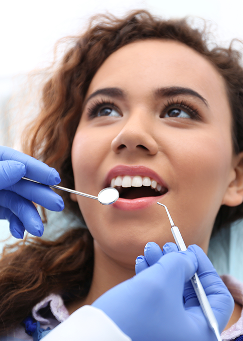 Woman smiling at dentist with dental tools around her.